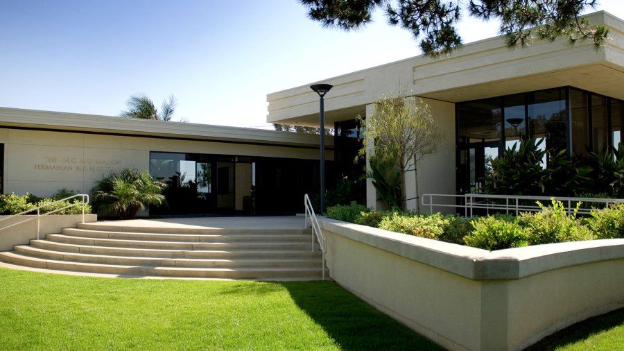 A green lawn gives way to several steps and a rectangular concrete and glass building.