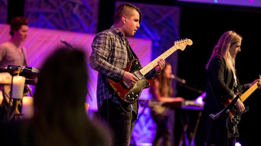Student playing guitar during worship