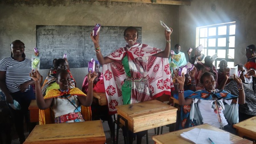 Women hold up feminine products as part of the period poverty research project