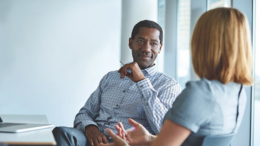 A older male therapist talks to a women during a counseling session.