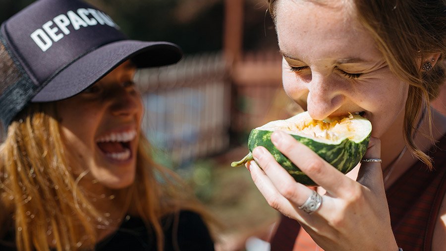 A member of the SEAA club looks on as her friend bites into a vegetable harvested from the garden.