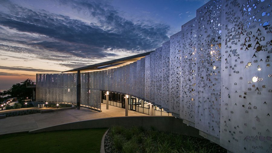 The alpha and omega metal pane wall sloping outward toward the twilight sky