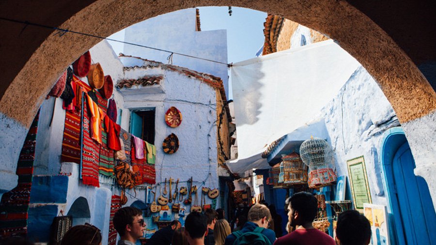 A group of students walk through a dense Moroccan market.