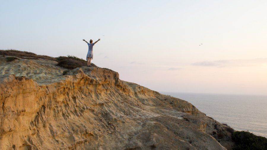 A PLNU student spreads her arms and watches the sunset on the San Diego cliffside.