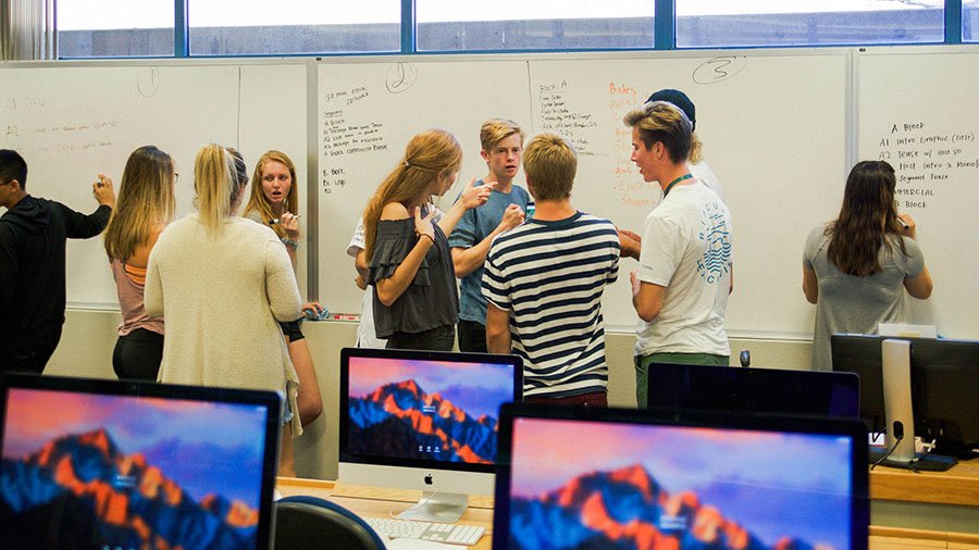 A class of students write on the front board and discuss a project.