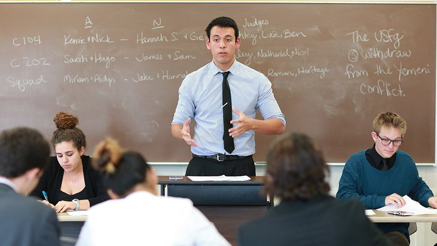 A speech and debate team member practices his argument in front of a his peers.