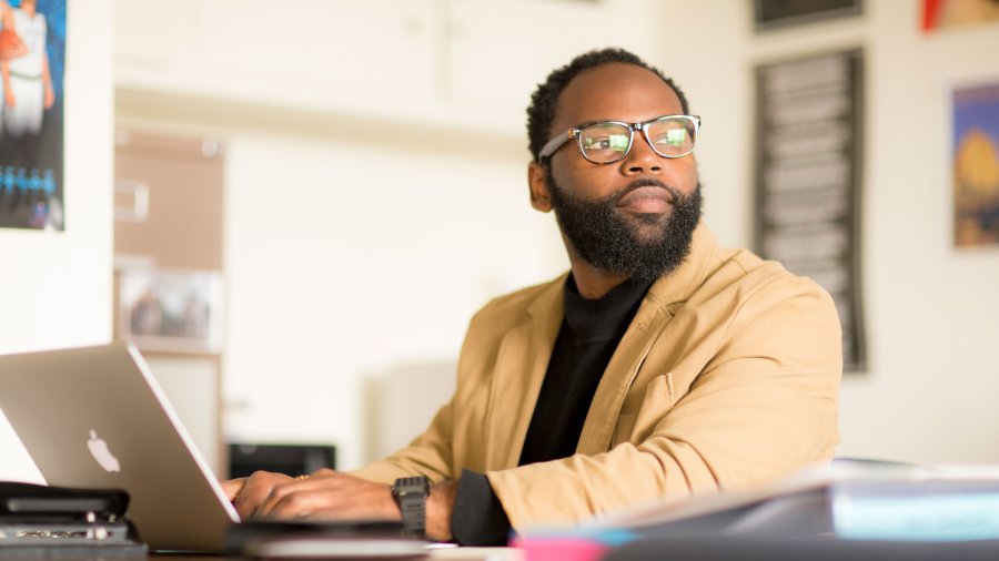 student with laptop looking into the distance