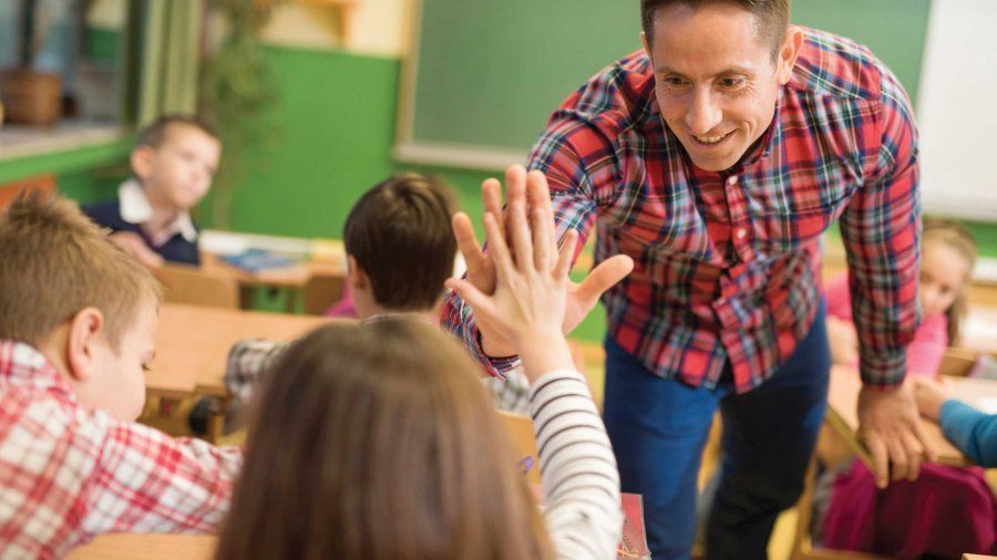 A male teacher hi-fives a student