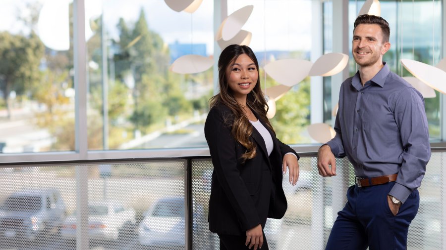 two students leaning over a railing looking past the photographer
