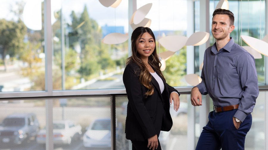 two students leaning over a railing  looking past the photographer