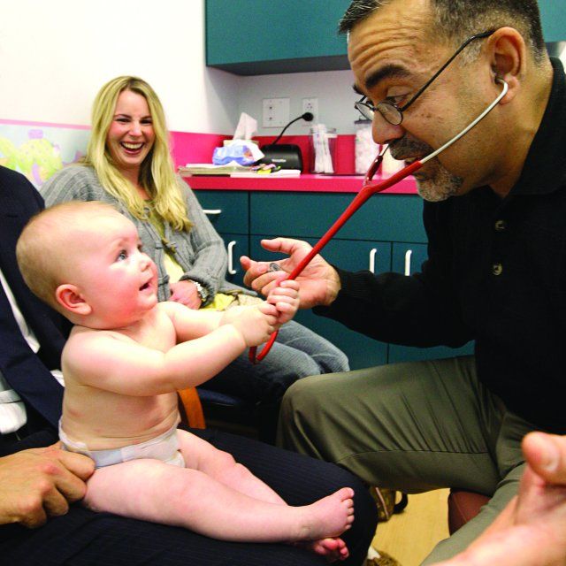 Dr. Rick Bravo playing with one of his infant patients as it grabs his stethoscope