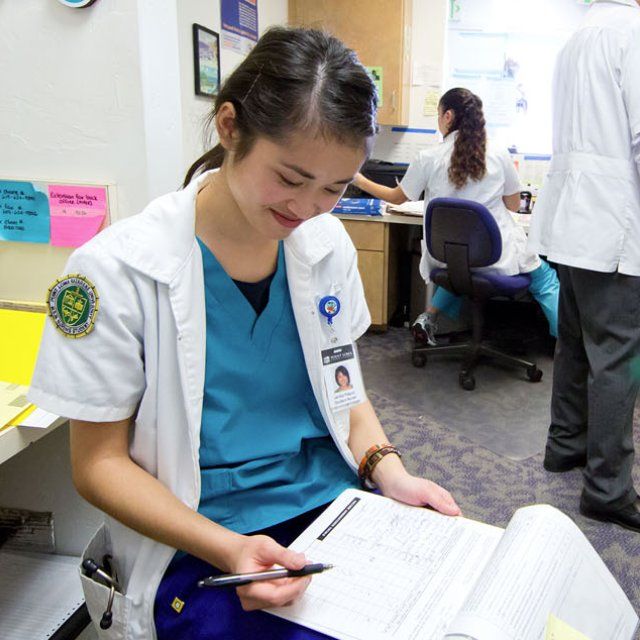 A PLNU nursing student writes down a report of her patient while in a medical office