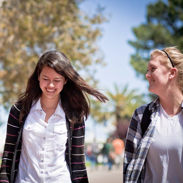 Two female PLNU students walk to out of chapel and head down caf lane on their way to class.