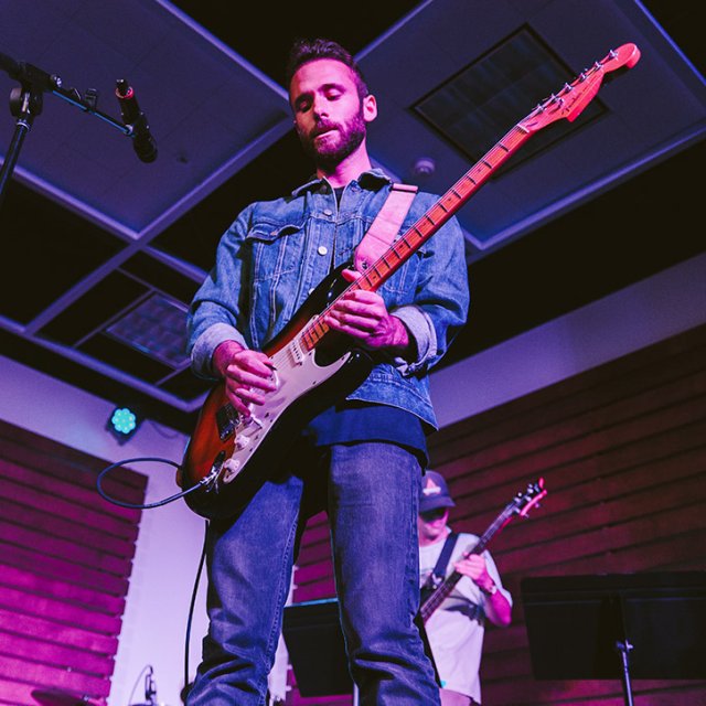 PLNU student Ian plays his guitar at a Musoffee night in the ARC.