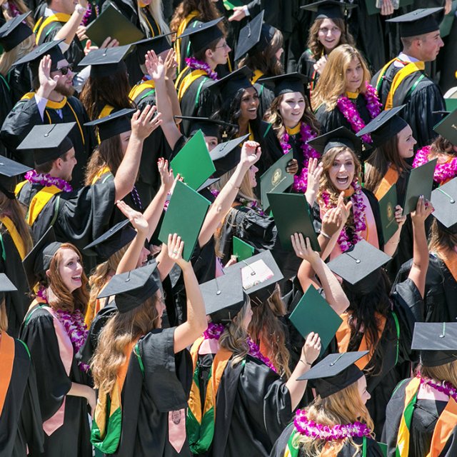 PLNU students in cap and gown celebrate receiving their diplomas during commencement