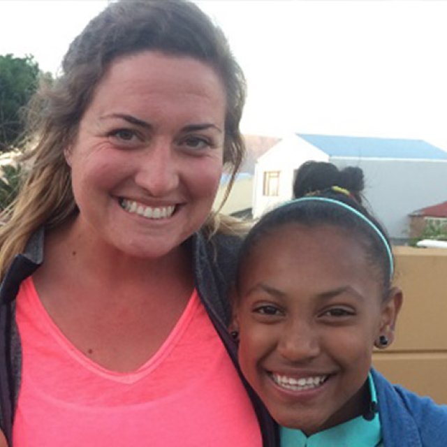 Nikki Romani stands outside in athletic clothes with her arm around a young woman
