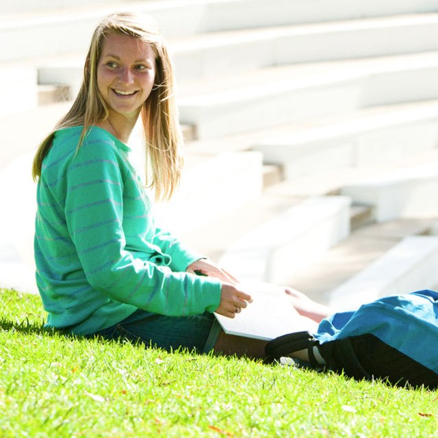 Female student sitting on the grass outside of the Greek Amphitheater