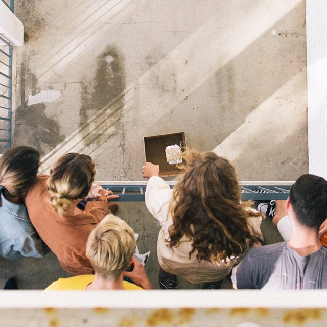 Students drop a protected egg from a balcony onto the concrete below as part of a science experiment