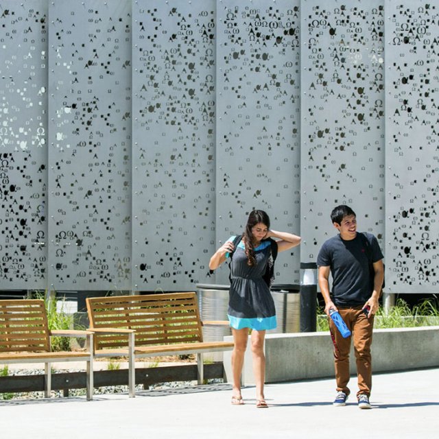 A male and female student walk to class during a sunny summer day