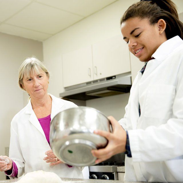 PLNU professor, Cindy Swann, helps a student prepare in meal in a food and nutrition class