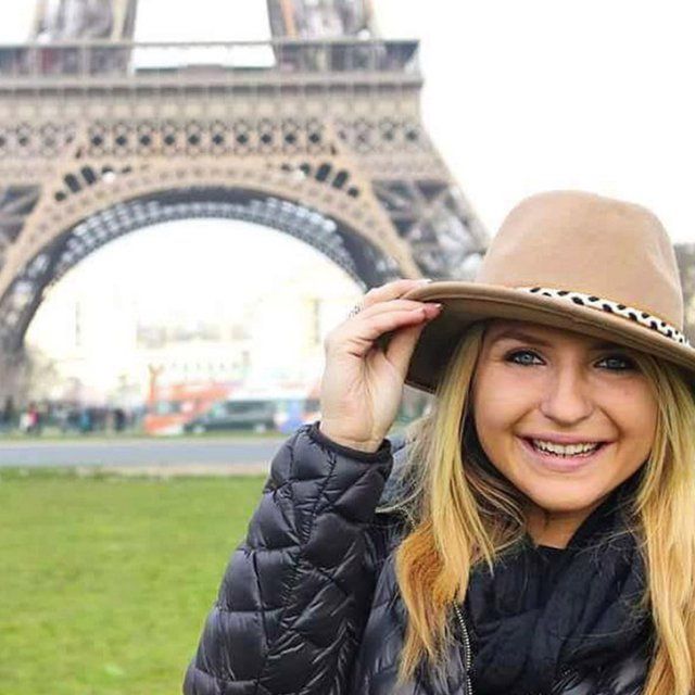 A PLNU student takes a photo in front of the Eiffel Tower in France. 