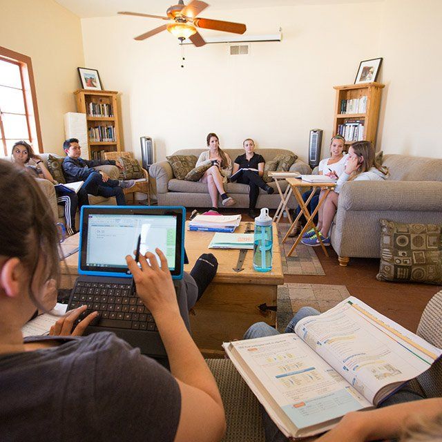 A group of students sit in a living room and have class as part of the community classroom experience