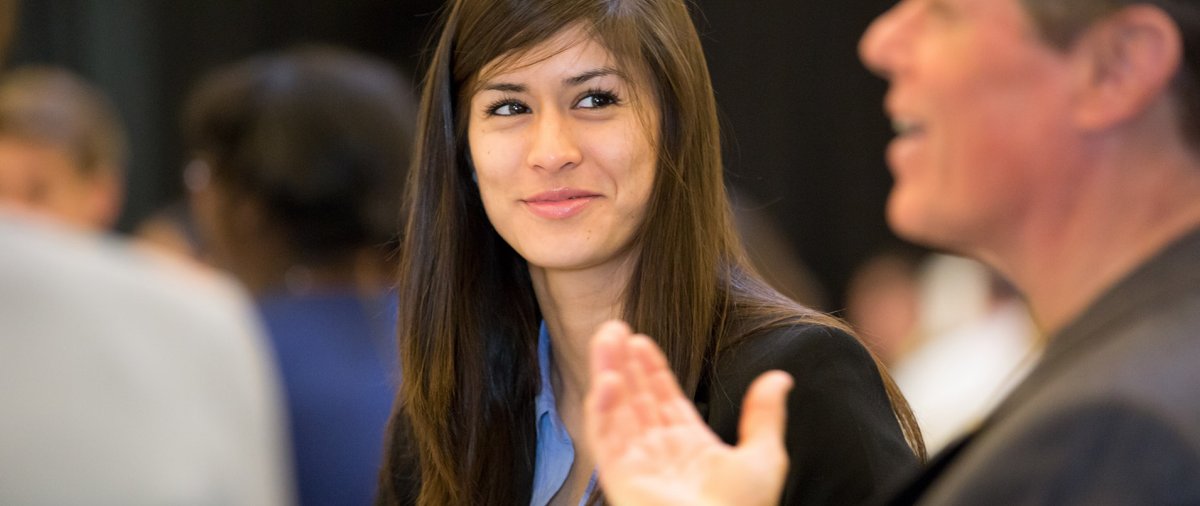A student listens intently to a speaker at a networking event