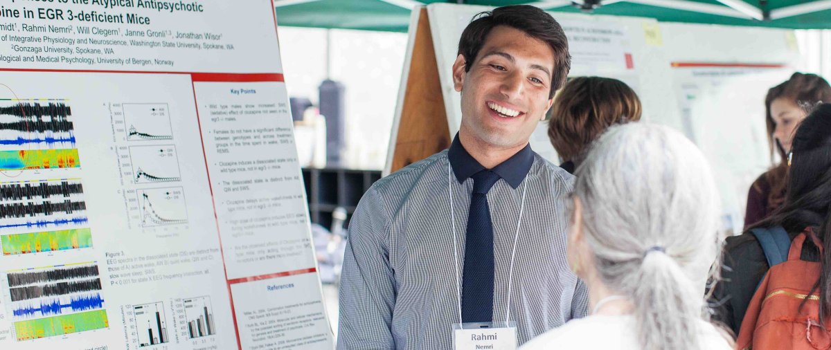 Researcher discusses a neuroscience poster with an attendee during a research conference.