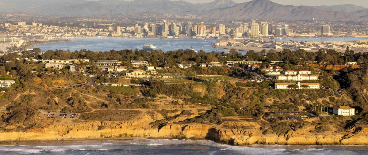 An aerial view of PLNU’s coastal campus with San Diego Bay, the downtown skyline, and mountains in the distance.