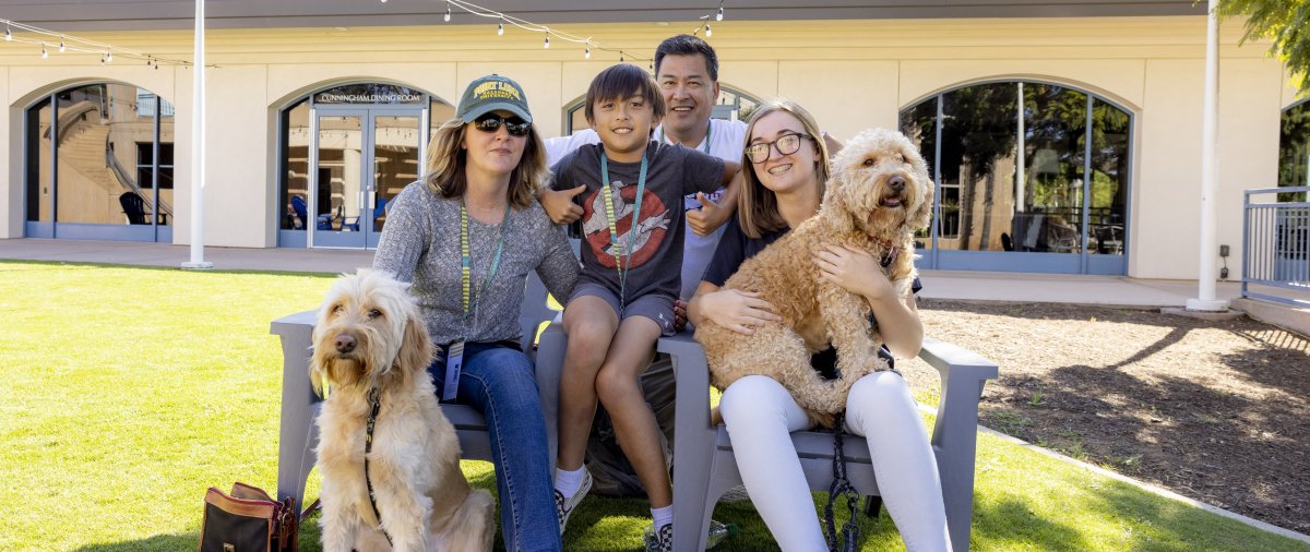 PLNU family posing together for picture with dogs on campus.