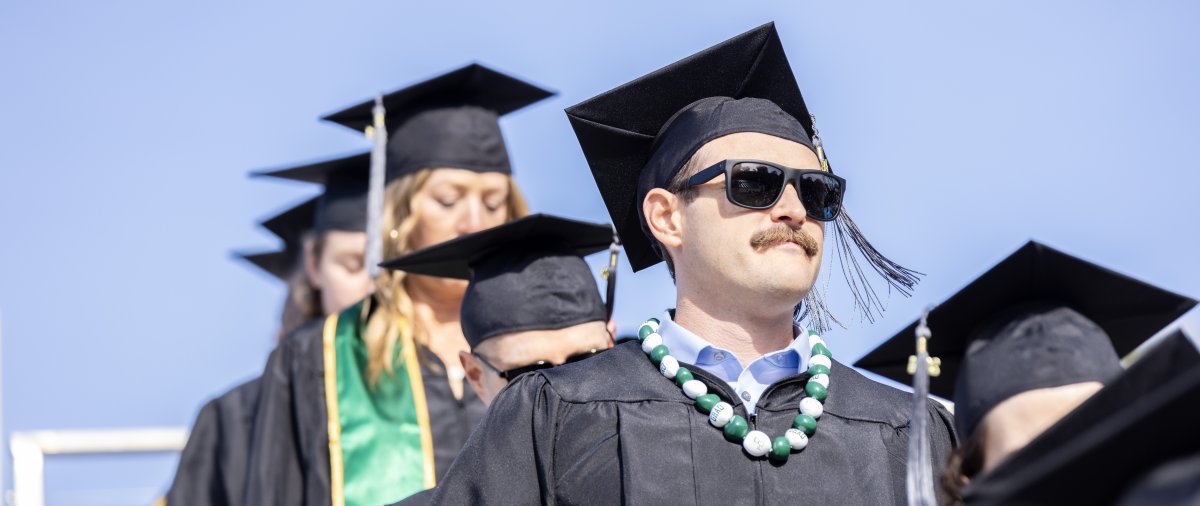 PLNU student walking to seat at graduation commencement.