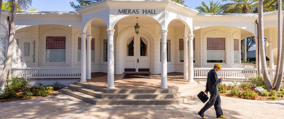 PLNU student walks across front entryway of Mieras Hall on university campus during the daytime.