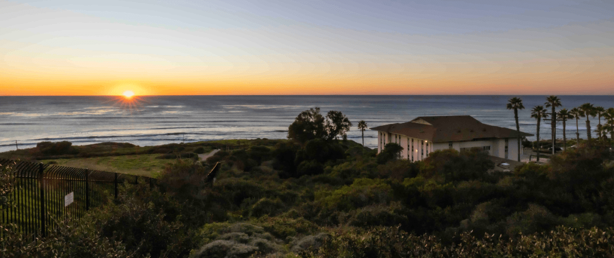 Sunset along Pacific Ocean horizon with Young Hall in shot.