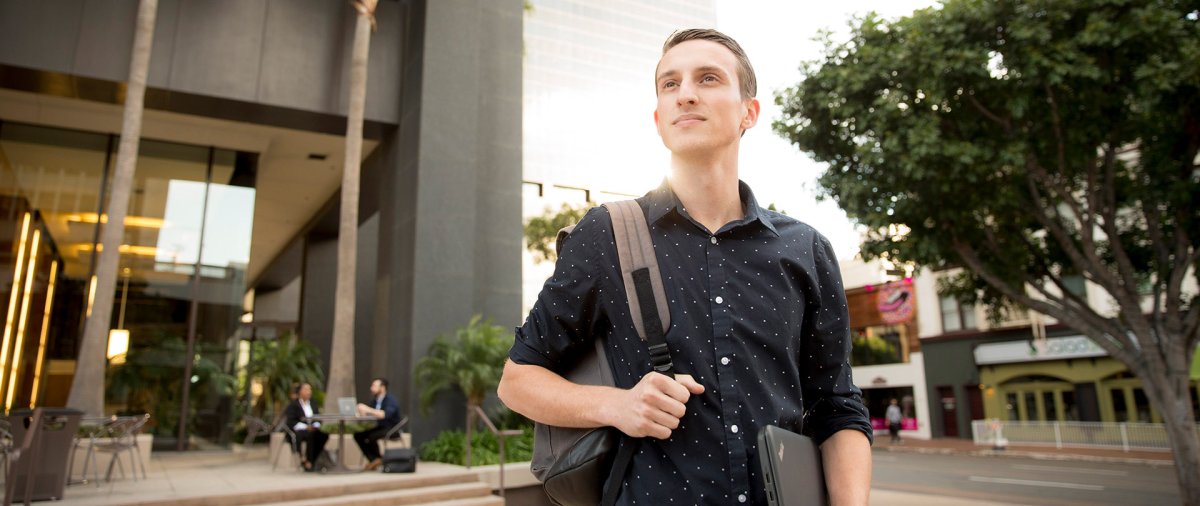 A well-dressed student looks across the street while in downtown San Diego.