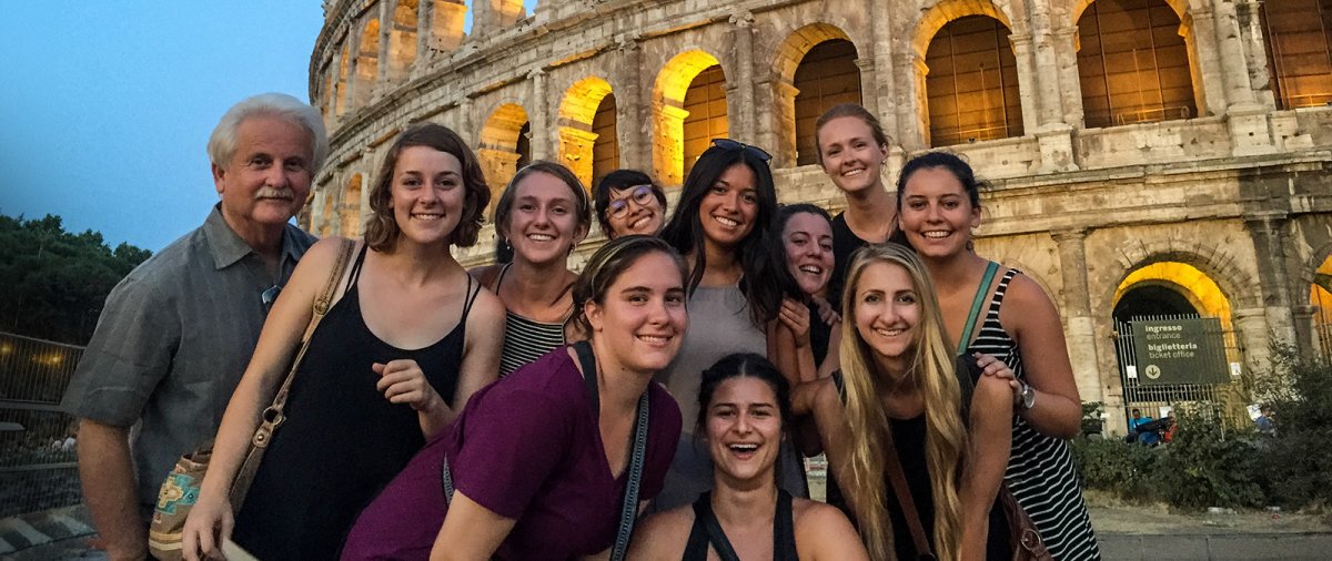 PLNU students with their professor all pose for a picture smiling in front of the Colosseum in Rome, Italy.