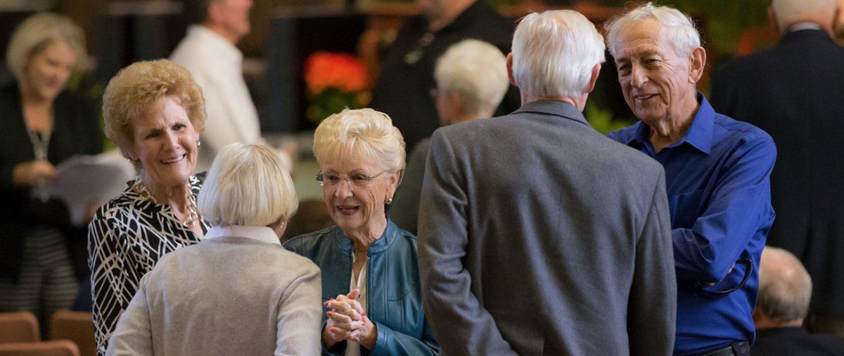 A group of older PLNU alums greet each other and catch up in Brown Chapel during Homecoming