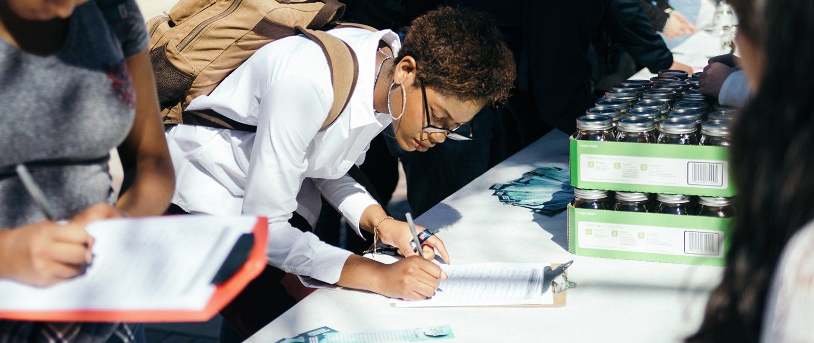 A student signs a pledge on a booth outside