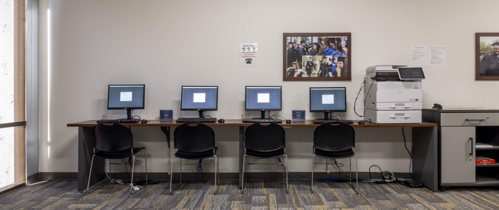 4 computers on a table next to a printer 