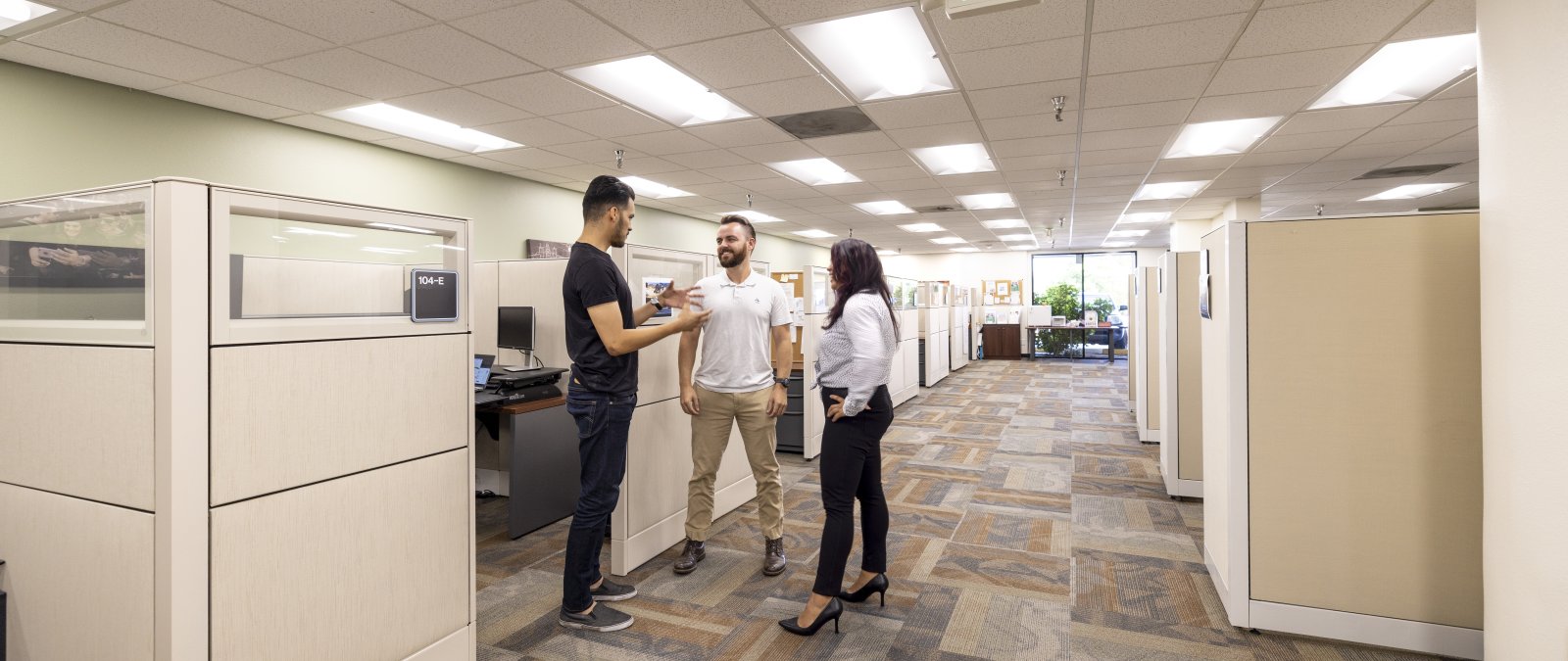 3 people gathered around an office having a conversation 