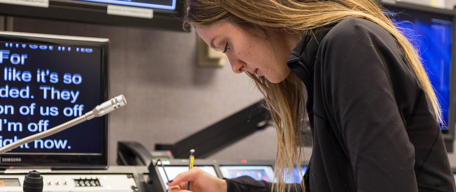 A student writes down notes in the production studio of Point TV.