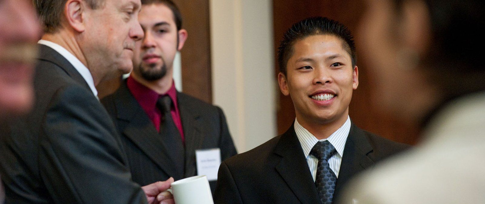 A professionally dressed business student networks at a PLNU business event.