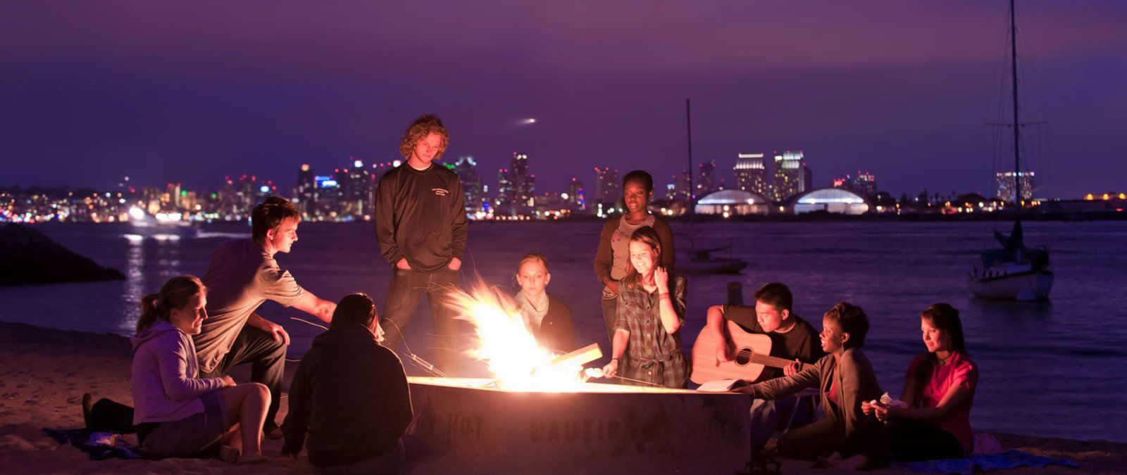 PLNU students have a beach bonfire at night and play music while at Shelter Island in San Diego.