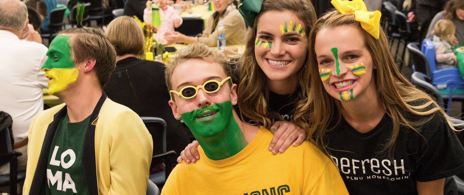 Students decked out in green and gold clothing have their faces colorfully painted for Homecoming.