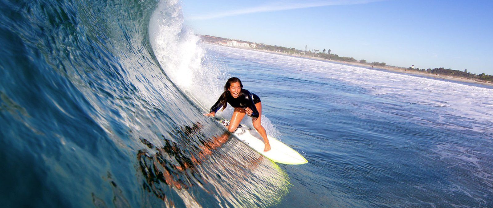 A PLNU female student surfs on a curling wave in San Diego