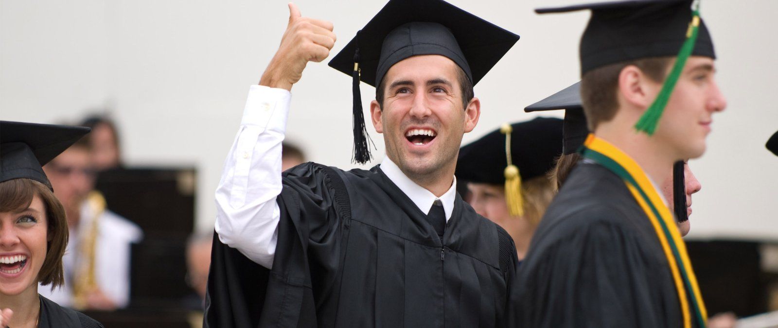 A graduating senior gives a thumbs up to his family in the audience