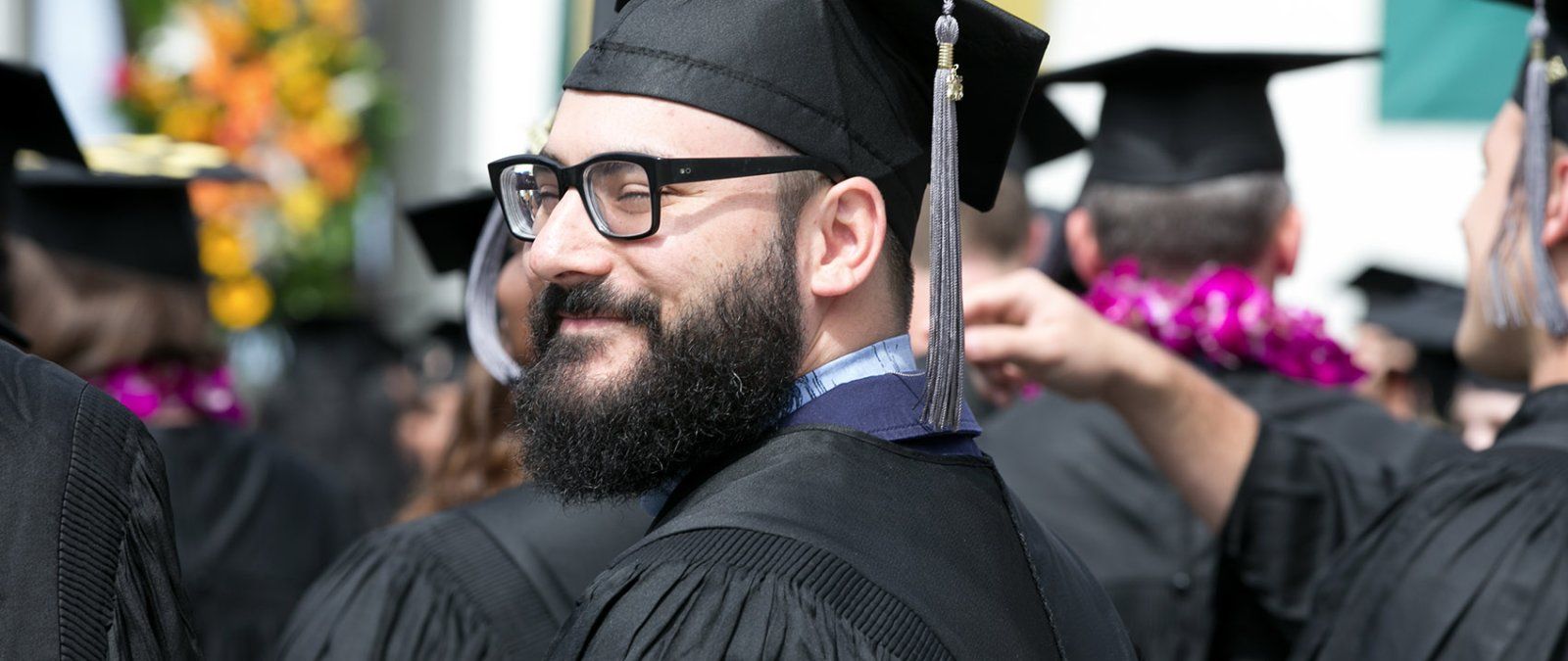 A PLNU graduate student smiles as he stands for graduation