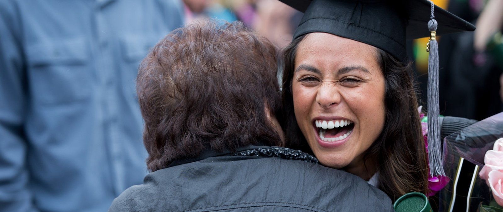 A PLNU graduate student is embraced by a grandparent after commencement.