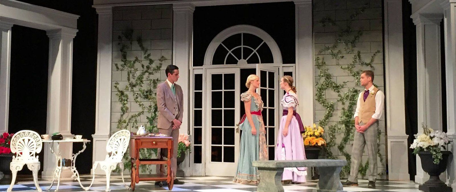Two men and two women gently conversing on the stage of The Importance of Being Ernest