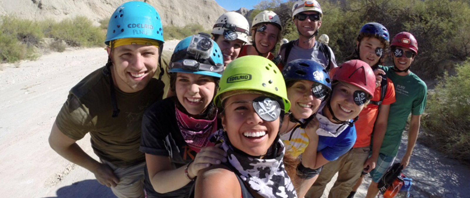 A group of students on a mud cave excursion take a photo together.