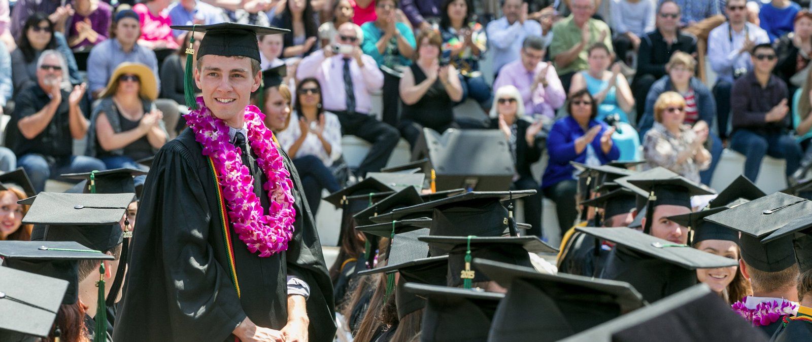 Jordan Thompson stands up to receive his diploma at PLNU's commencement ceremony
